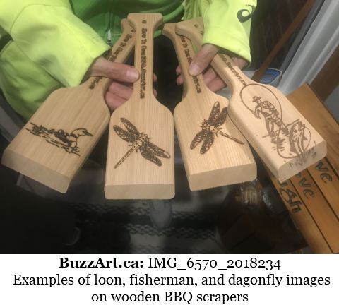 Examples of loon, fisherman, and dagonfly images on wooden BBQ scrapers